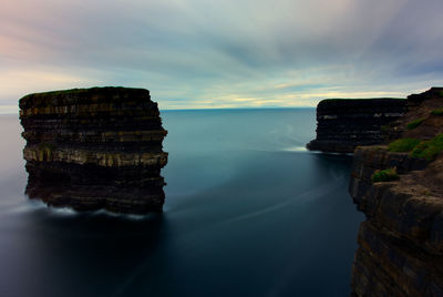 Rock formations in sea against sky during sunset