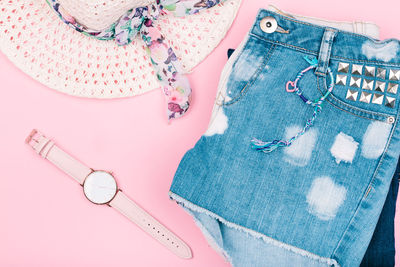 High angle view of clothing and wristwatch against pink background