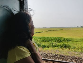 Woman looking through window while sitting in train