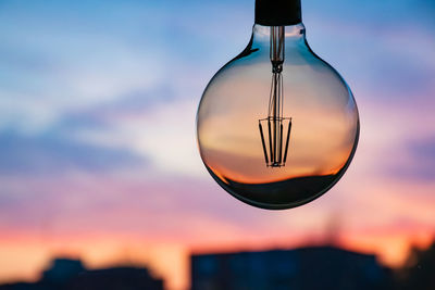 Close-up of glass against sky during sunset