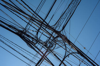 Low angle view of electricity pylon against clear blue sky