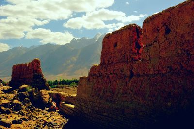 Rock formations on mountain against cloudy sky