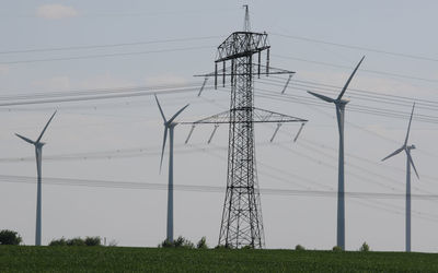 Low angle view of electricity pylon on field against sky