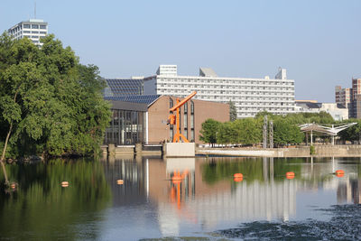 Buildings by lake against sky in city