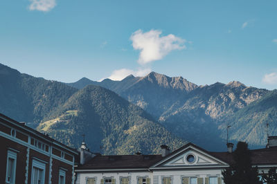 Residential buildings by mountains against sky