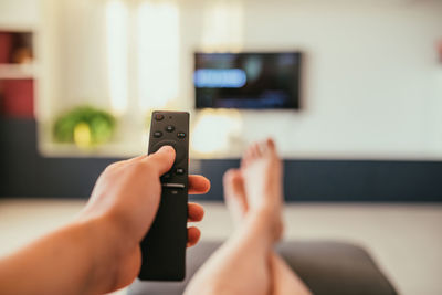 Low section of woman using mobile phone at home