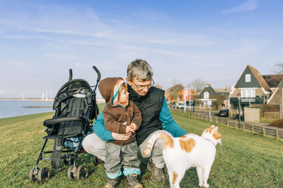 Full length of serious man with grandchild looking at cat