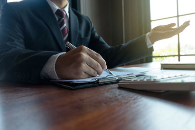 Midsection of man with umbrella on table