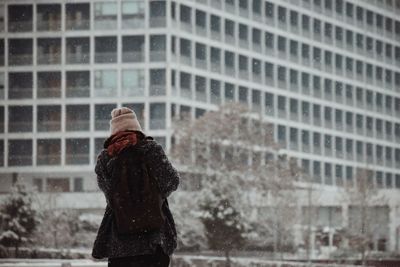 Rear view of woman standing in city during winter