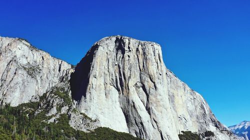 Low angle view of rock formations against clear blue sky
