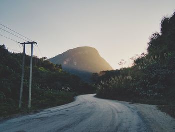 Road amidst trees against sky during sunset