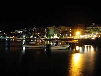 Boats in illuminated canal at night