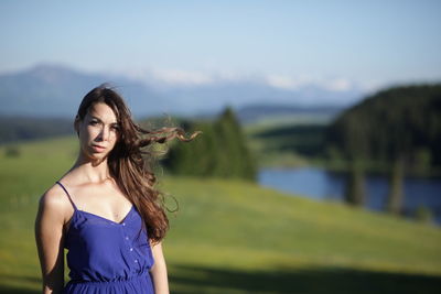 Portrait of beautiful young woman standing on field