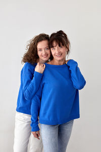 Delighted mother and daughter in similar sweaters in studio