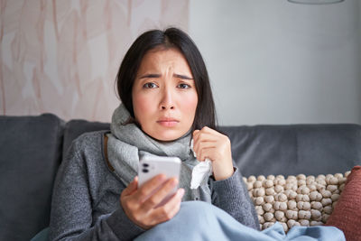 Portrait of young woman sitting on sofa at home