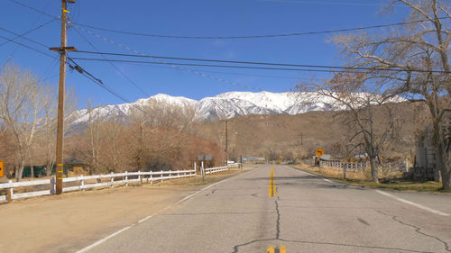 Road by trees against sky during winter