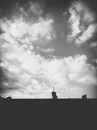 Silhouette built structures against cloudy sky