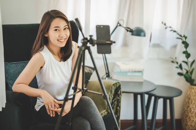 Portrait of smiling young woman sitting on chair at home