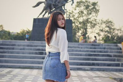 Young woman standing against steps