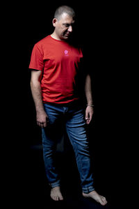 Man looking away while standing against black background