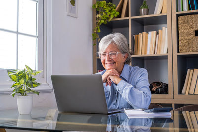 Young woman using laptop while sitting on sofa at home