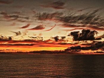 Scenic view of sea against dramatic sky during sunset