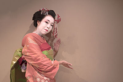 Young woman standing against wall