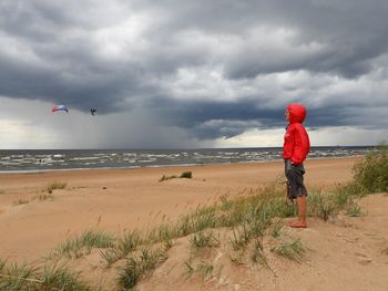 Boy standing on beach against sky