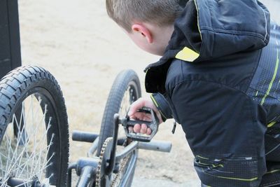 Rear view of boy standing by bicycle