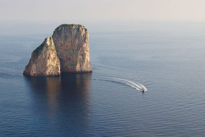 Rock formation in sea against sky