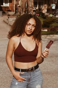 Portrait of woman holding ice cream while standing on road