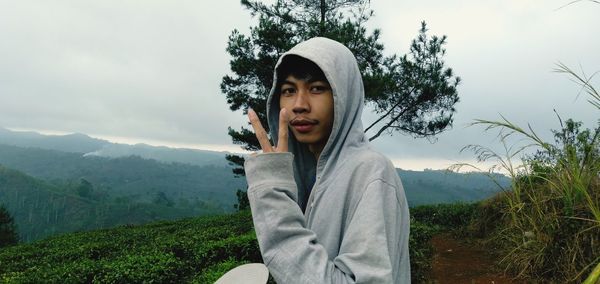 Portrait of young man showing peace sign on mountain