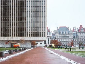 Road by buildings in town against sky