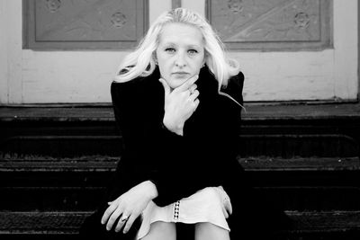 Portrait of young woman seated on stairs.