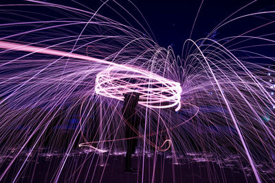 Silhouette man spinning wire wool on field at night