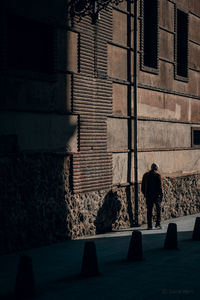 Rear view of people walking on building wall
