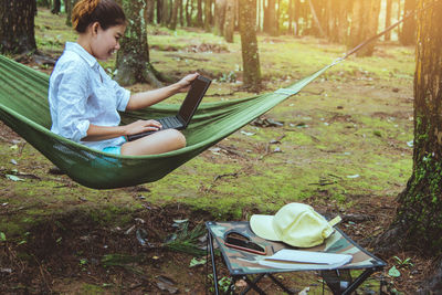 Woman using laptop while sitting in hammock