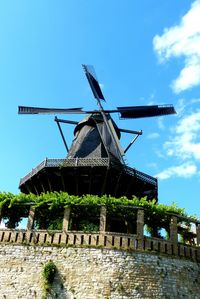 Low angle view of traditional windmill against blue sky