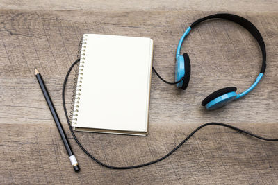 High angle view of headphones with book and pencil on table