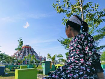 Side view of woman looking at park against sky