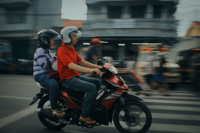 People riding motorcycle on street in city