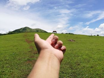 Midsection of man holding hands on field against sky