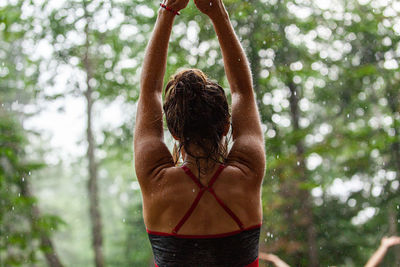 Rear view of shirtless man standing in forest