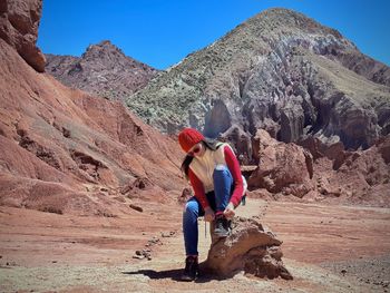 Rear view of woman sitting on rock