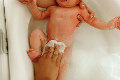 Cropped mother bathing newborn son in bathtub