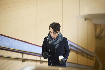 Man with coffee cup walking upstairs