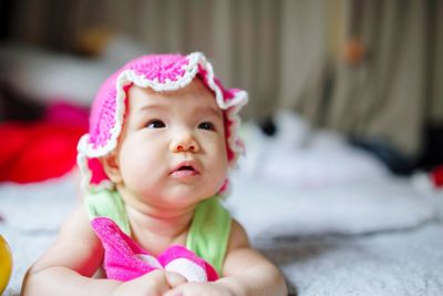 Cute baby girl looking away while lying on bed