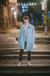 Portrait of young man standing against staircase