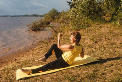 Young woman sitting on land by sea