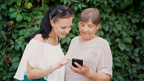 Female friends using smart phone outdoors